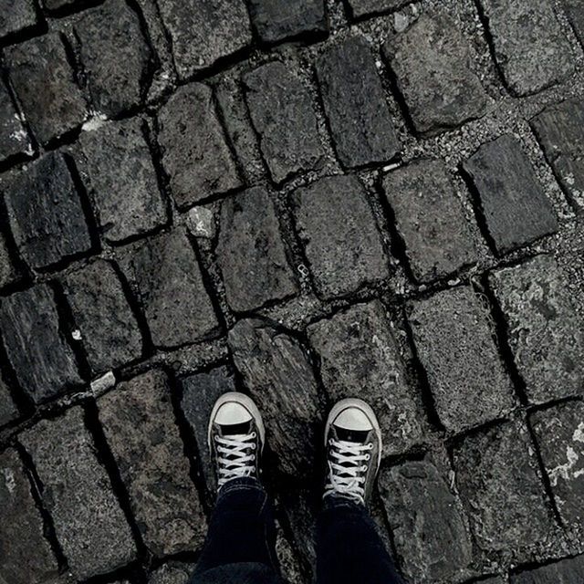 low section, person, shoe, standing, personal perspective, high angle view, lifestyles, human foot, footwear, directly above, cobblestone, men, street, unrecognizable person, leisure activity, jeans, footpath