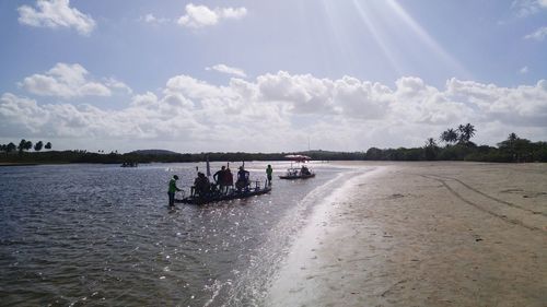 People in boat on shore at beach against sky