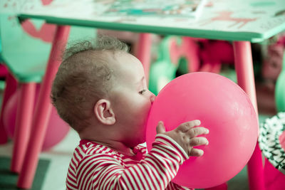 Close-up of cute boy with pink balloons