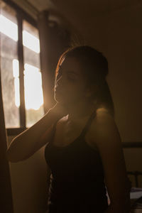 Young woman looking away by window at home