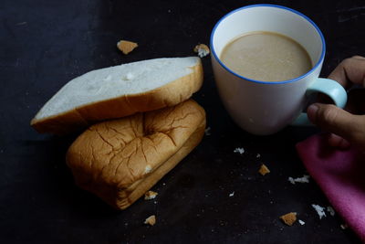 High angle view of hand holding coffee cup on table