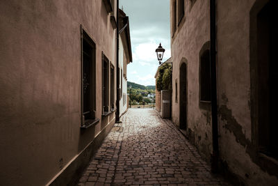 Walkway amidst buildings against sky