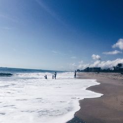 People on beach against blue sky