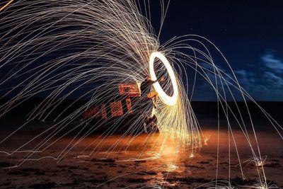 Man with wire wool at beach against sky
