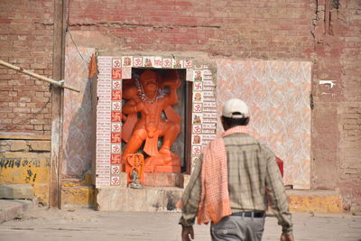 Rear view of people walking against brick wall