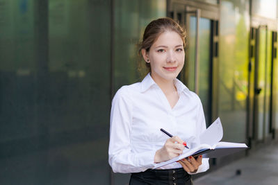 Successful business woman making notes in notebook outdoors in business