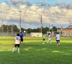 People playing soccer on field against sky