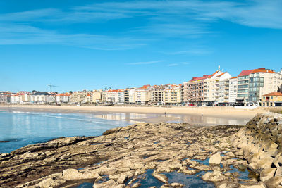 Buildings by sea against sky