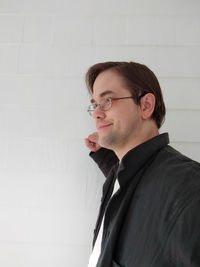 Portrait of young man looking away while standing against wall