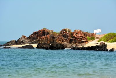 Rock formations in sea against clear blue sky