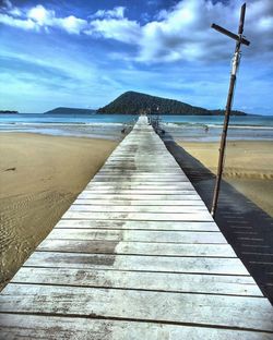 Pier on sea against cloudy sky