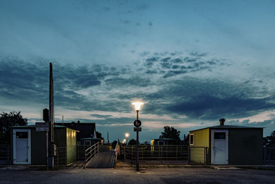 Street by buildings against sky during sunset