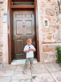 Full length of boy standing by door of building