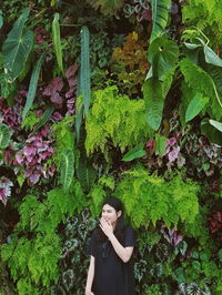 Young woman standing by plants