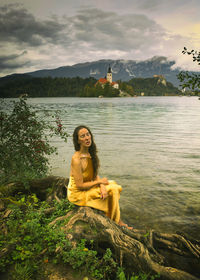 Woman in yellow dress sitting on the shores of lake bled, slovenia iv