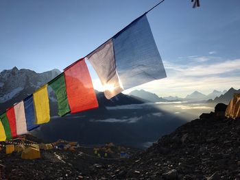 Low angle view of flags hanging on rock against sky