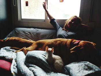 Young woman sitting in the bed with her pets 