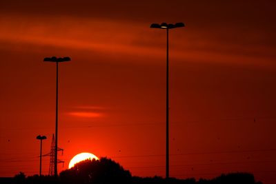 Illuminated street light against orange sky