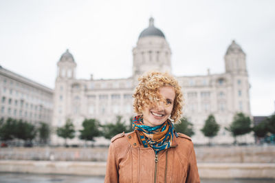 Portrait of smiling woman standing against buildings in city