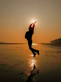 Silhouette person on beach against sky during sunset