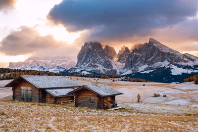 Houses by snowcapped mountains against sky during winter