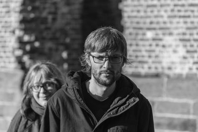 Portrait of young man wearing eyeglasses and jacket in city