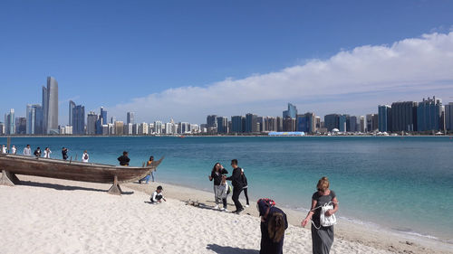 People on beach by buildings against sky