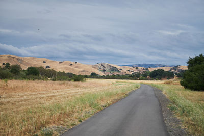 Road amidst field against sky