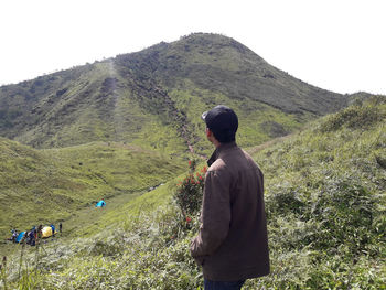 Rear view of man climbing on mountain against sky