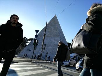 Men walking in city against clear sky