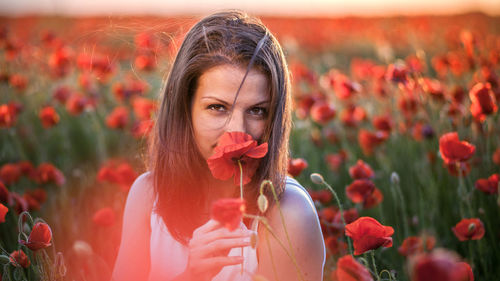 Close-up portrait of young woman with poppy flowers
