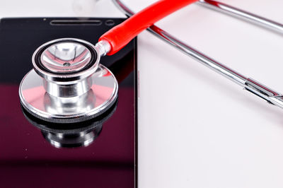 Close-up of stethoscope with mobile phone against white background