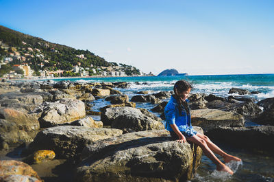 Girl sitting on rock at the seaside