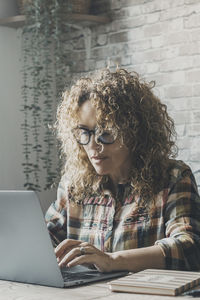 Young woman using laptop while sitting on table