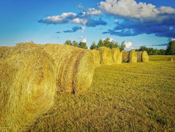 Hay bales on field against sky