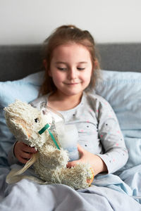 Happy girl with toy on bed at home