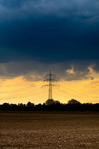 Silhouette electricity pylon on land against sky during sunset