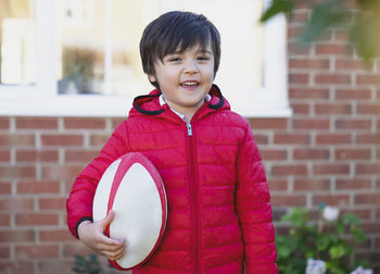 Portrait of smiling girl standing against brick wall