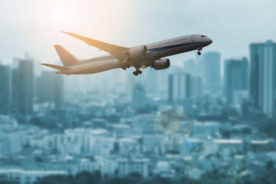 Airplane flying over city against sky