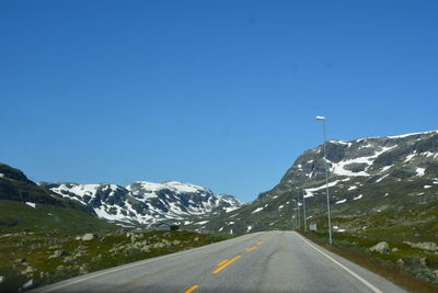 Road amidst mountains against clear blue sky