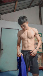 Full length of shirtless man standing against wall