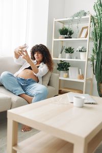 Young woman using mobile phone while sitting at home