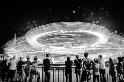 People at amusement park against sky at night
