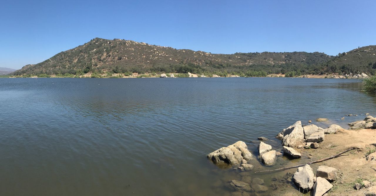 SCENIC VIEW OF SEA AND MOUNTAINS AGAINST CLEAR SKY