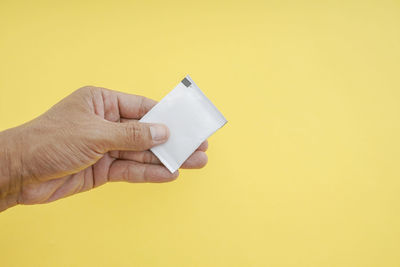 Midsection of person holding umbrella against yellow background