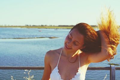 Young woman standing by sea against clear sky