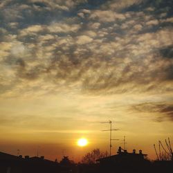 Silhouette of communications tower against sky during sunset