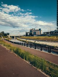 Road by bridge in city against sky