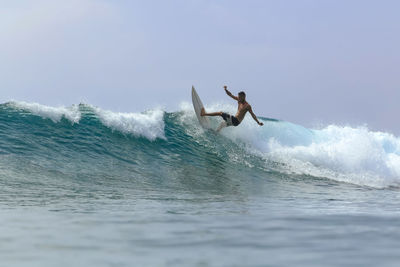 Man surfing in sea against sky