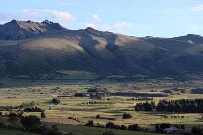 Scenic view of farms and mountains against sky